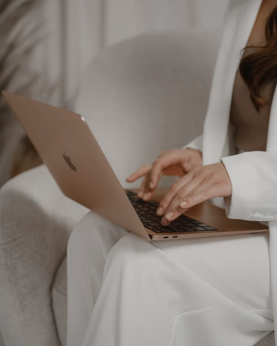Woman in white working on a laptop during a telehealth visit