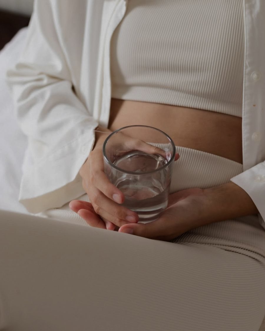 Woman in cream loungewear holding a glass of water